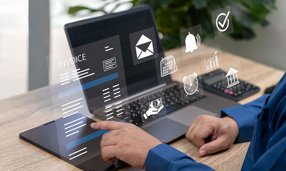 Person using digital tools on a laptop for invoicing and financial management, with interactive icons.