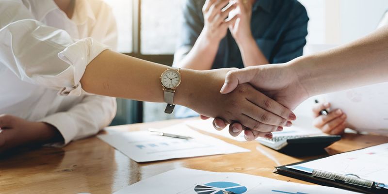 Business meeting handshake with charts on table, teamwork concept.