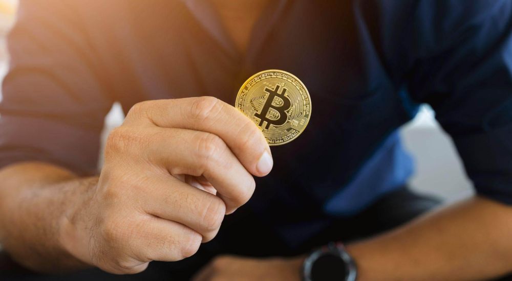 a man holding a bit coin in his hand