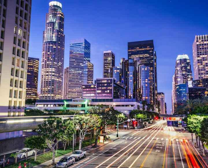 Downtown Los Angeles skyline at dusk with vibrant lights and traffic trails, showcasing urban life and architecture.