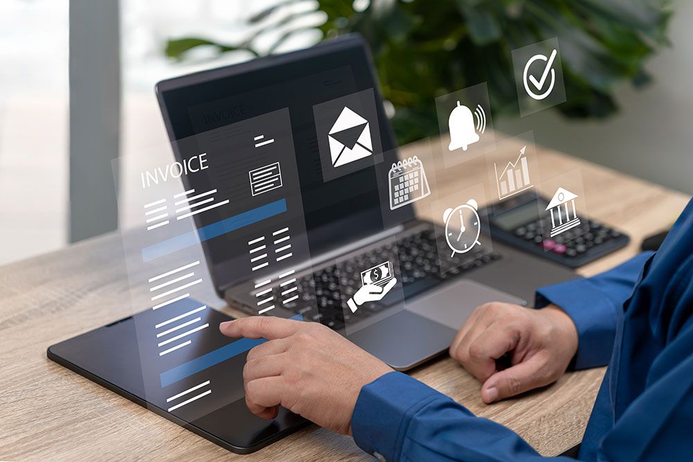 Person using digital tools on a laptop for invoicing and financial management, with interactive icons.