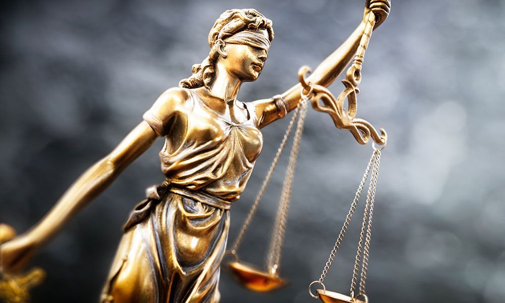 Blindfolded Lady Justice statue holding scales, symbolizing fairness and law.