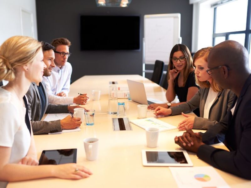 Business team in a meeting discussing strategy with documents and laptops in a modern conference room.
