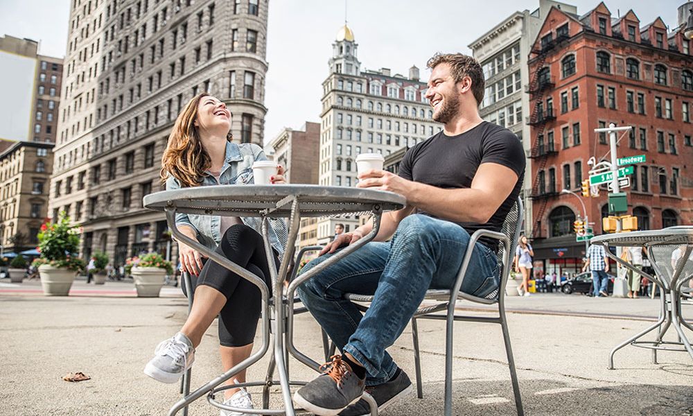 A happy couple enjoying coffee at an outdoor café near the Flatiron Building in New York City.