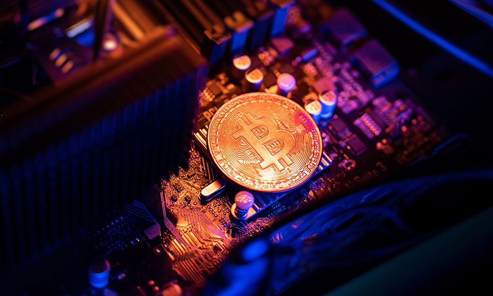 Bitcoin coin on a computer motherboard, representing cryptocurrency mining and blockchain technology.