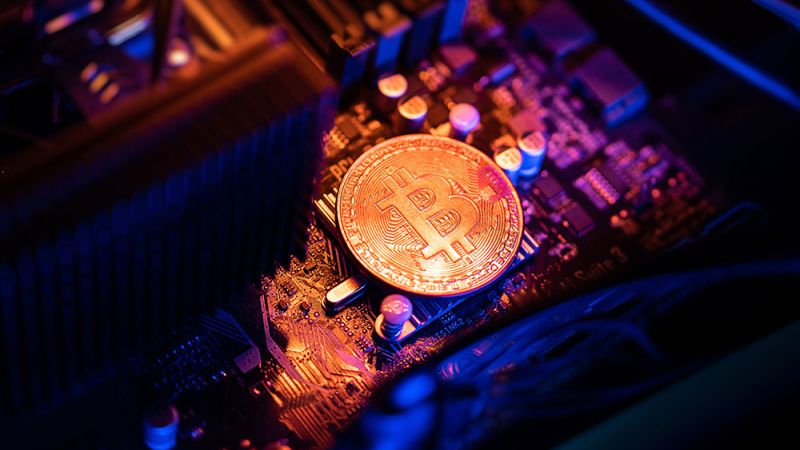 Bitcoin coin on a computer motherboard, representing cryptocurrency mining and blockchain technology.