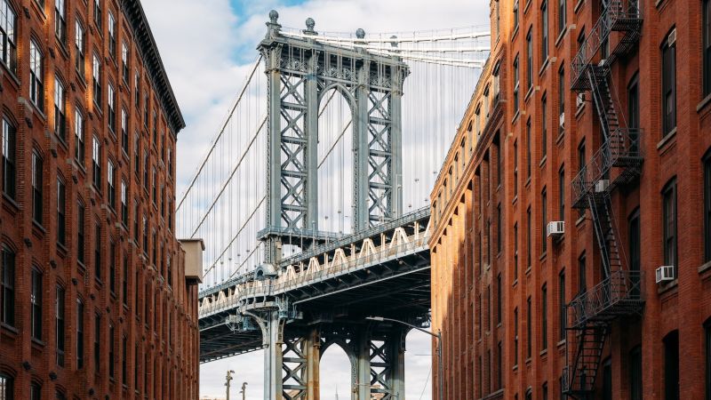 Iconic bridge framed by red brick buildings under a blue sky. Urban cityscape with architectural contrast.