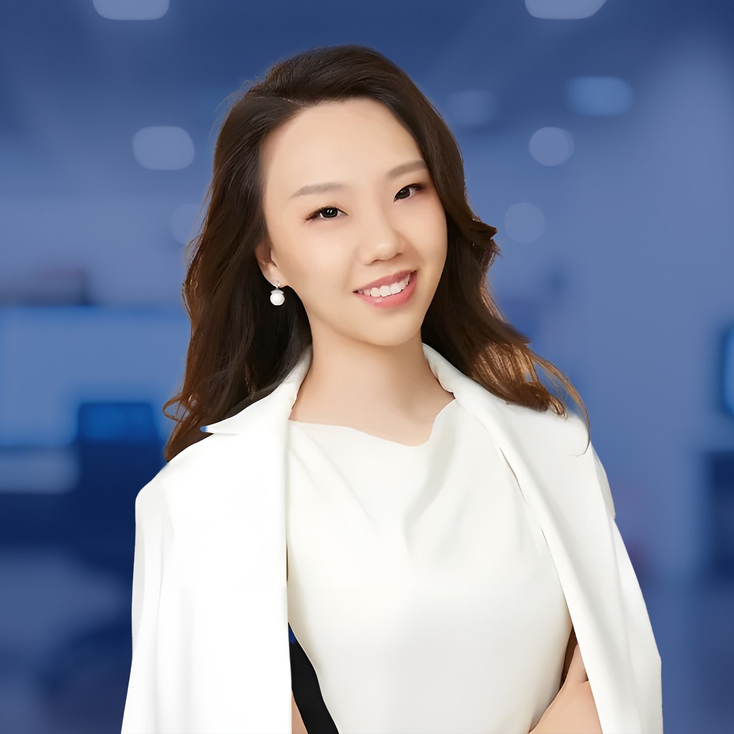 Smiling woman in a white outfit with a blurred office background.