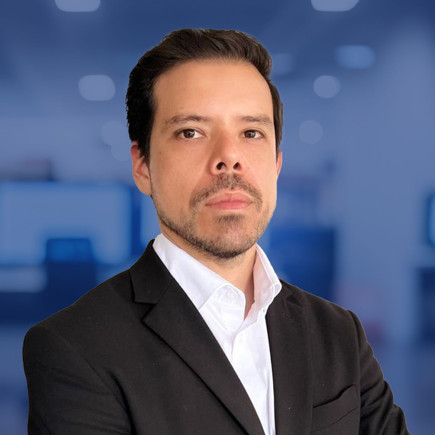 A person in a suit in an office setting, with a confident expression, facing forward.