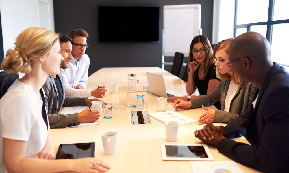 Business team in a meeting discussing strategy with documents and laptops in a modern conference room.