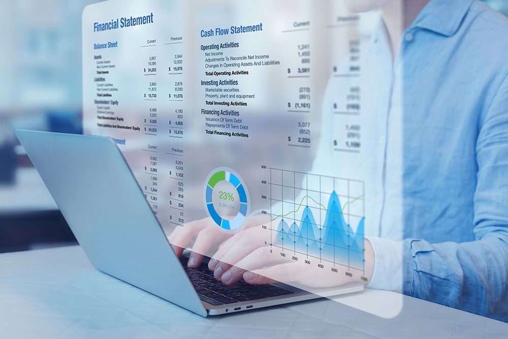 Person analyzing financial data on laptop with balance sheet and graphs.