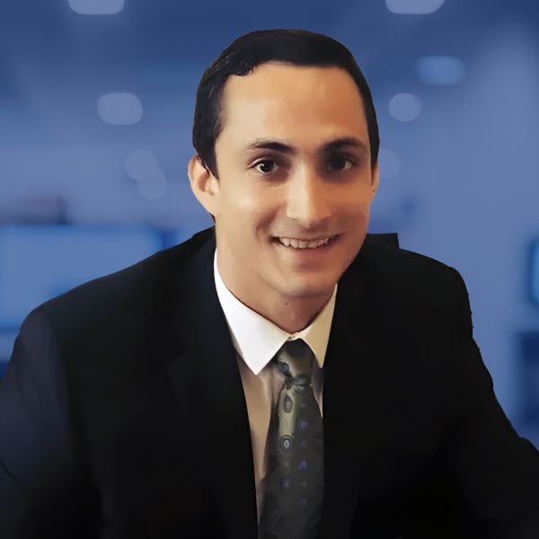 Smiling professional in a suit with a blurred office background, representing business leadership or corporate success.
