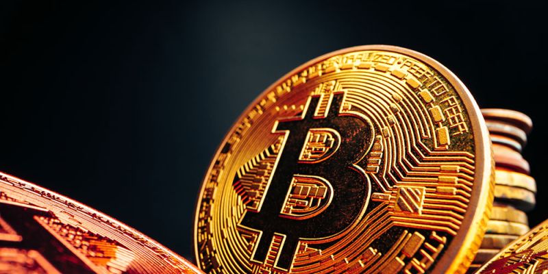 Close-up of shiny gold Bitcoin coins with cryptocurrency symbol on a dark background.