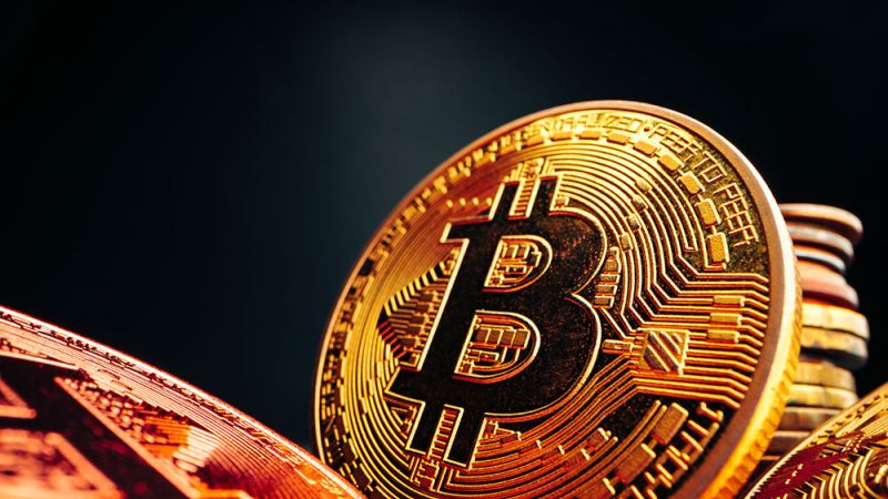 Close-up of shiny gold Bitcoin coins with cryptocurrency symbol on a dark background.
